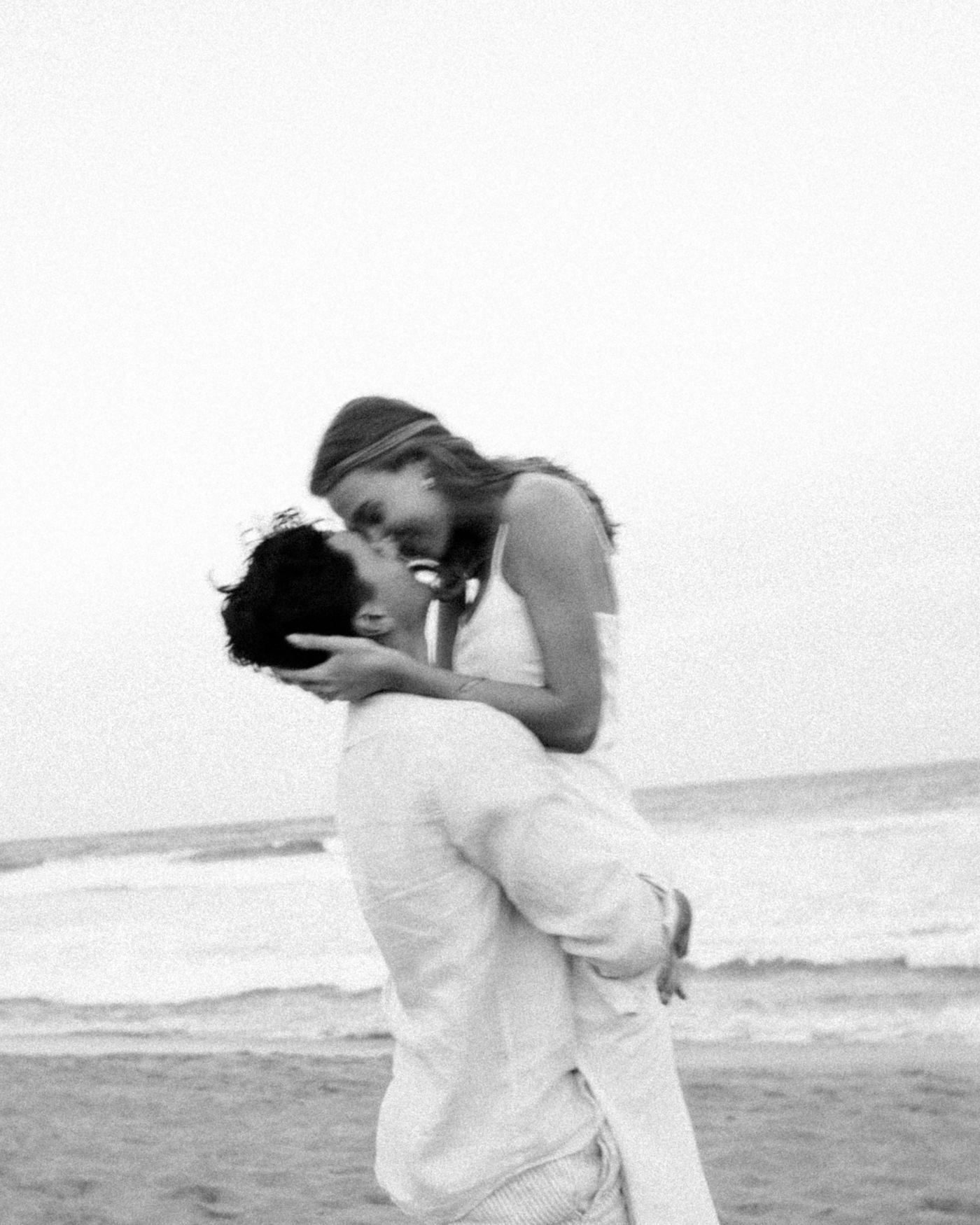 Connor lifting Grace on the beach as they kiss
